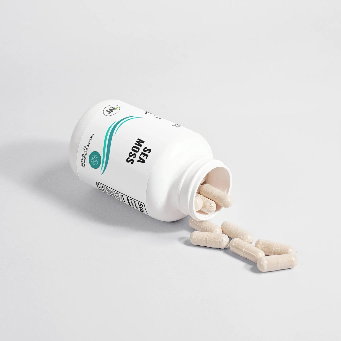 An open bottle of Nutrition Tribune's Organic Sea Moss supplement lying on its side with several capsules spilling out.